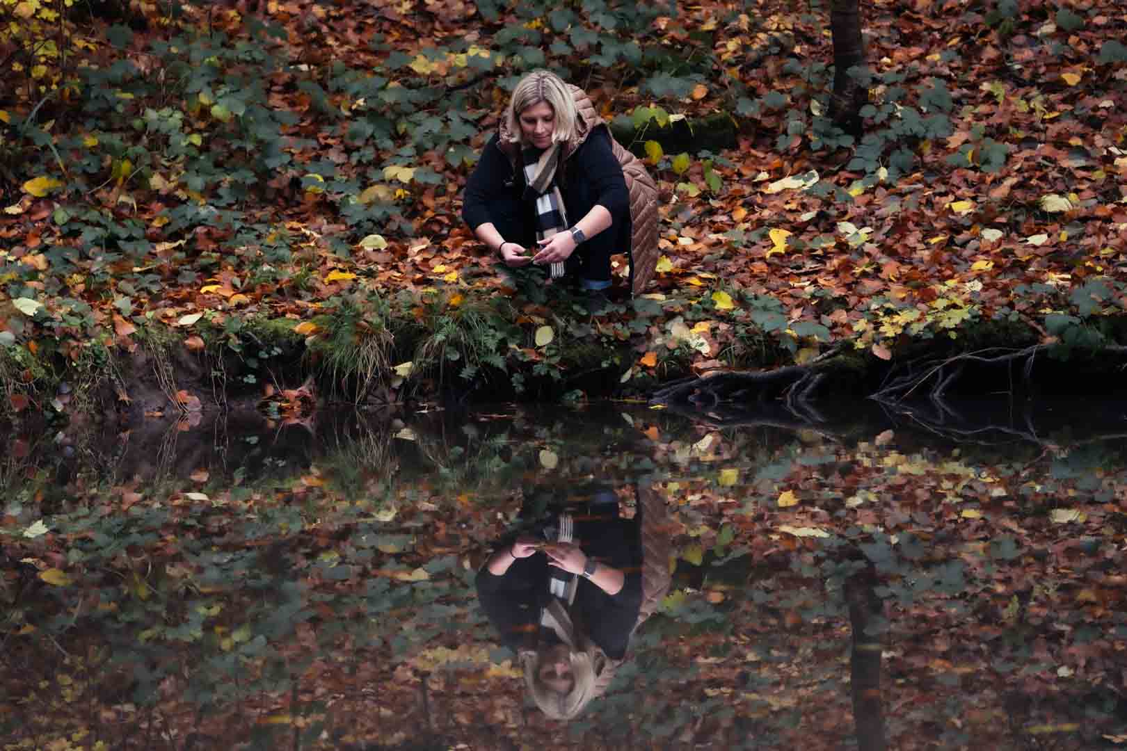 Frau wirft Blätter in einen See